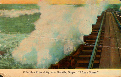 This image from the 1910s shows the railroad line running across the top of South Jetty. The railroad was built on a trestle over the open water and used to transport riprap (rocks) which were piled around the trestle until all that could be seen was the railroad grade running atop the jetty. Before this was completely done, however, the Admiral crashed into the only part of the jetty that hadn't been filled in with riprap, in 1912. A wave breaks over South Jetty in this colorized picture postcard image from the 1910s. This railroad line is the one used to rescue the crew of the shipwrecked schooner "Admiral" after a wave wedged it into the unfinished jetty.