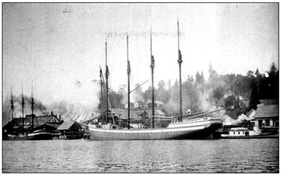 At 683 tons, the four-masted schooner Admiral was big for a sailing ship in the coastal service. This image shows the ship in her home port of North Bend. Four-masted schooner Admiral in its home port of North Bend, taking on a cargo of lumber.