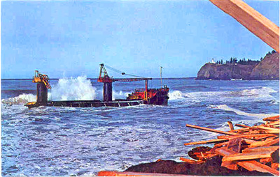 The doomed lumber barge George Olson aground on Clatsop Spit. In the foreground is a jumble of cargo that washed off its decks; in the background, Cape Disappointment Lighthouse. Doomed lumber barge George Olson aground on Clatsop Spit.
