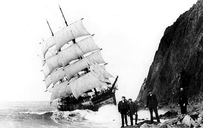 Neahkahnie Mountain is much closer to the Glenesslin than most skippers would want it. Under almost full sail, the doomed Glenesslin grinds against the side of Neahkahnie Mountain as its crew members pose for the camera.