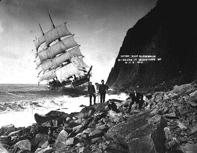 Note the full suit of sails hanging from the Glenesslin's masts. The only canvas not out and full of wind were the three topsails. Crew members pose in front of the Glenesslin, stranded on the rocks by Neahkahnie Mountain.