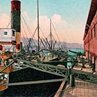 This postcard picture from the 1910s shows a steamer at a dock in Portland being loaded with wheat using conveyer belts. The men tending the belts, loading and unloading 200-plus-pound sacks of wheat, are longshoremen.