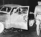Investigators look over Larry Peyton’s car after his body has been removed, on Sunday, Nov. 27, 1960.